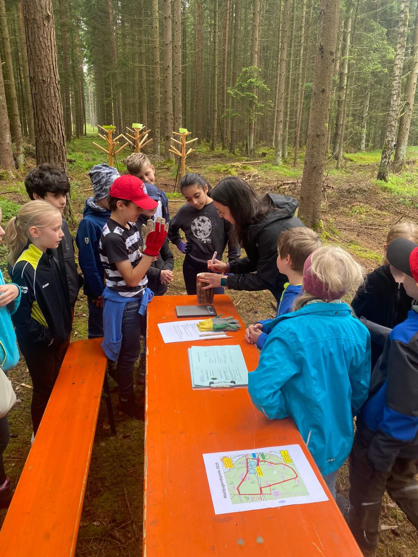Kinder mit Frau im Wald bei einem Spiel mit Waage